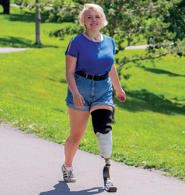 Une adolescente amputée d’une jambe marche sur un sentier dans un parc.