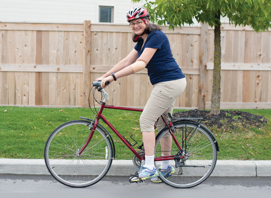 Une femme adulte amputée d’un bras fait du vélo dans une rue.
