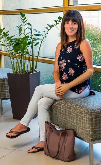 Une femme amputée d’un bras est assise à l’intérieur sur un banc.