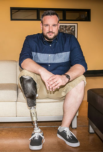 Un homme amputé d’une jambe est assis sur un divan.