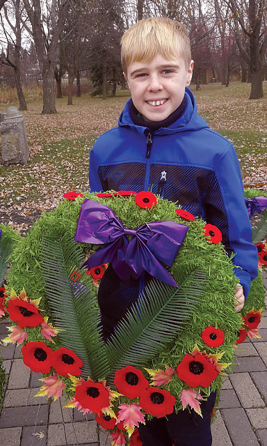 Un enfant amputé tient une couronne lors d’une cérémonie du jour du Souvenir.