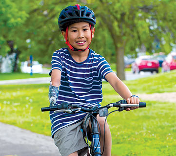 Étienne, a right arm amputee, riding his bike using a cycling device attached to the handlebar.