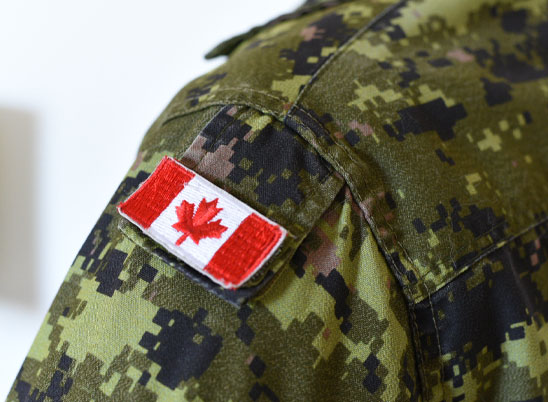 Gros plan de l’épaule d’un uniforme des Forces armées canadiennes muni d’un écusson du drapeau canadien.