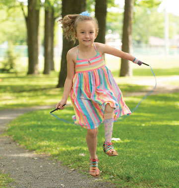 Une enfant amputée de la main gauche et de la jambe gauche saute à la corde grâce à son aide technique.