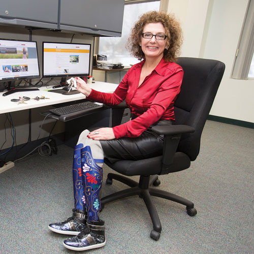 A female adult double-leg amputee sits at her desk at The War Amps Key Tag Service.