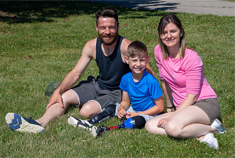 Dylan sitting on a lawn with his mother and father.