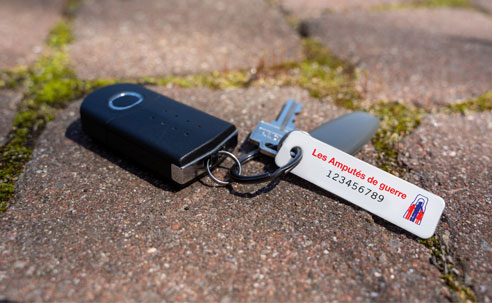 Une plaque porte-clés est attachée à un trousseau de clés qui est sur le sol.