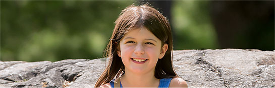 A young female child amputee sitting on a rock.