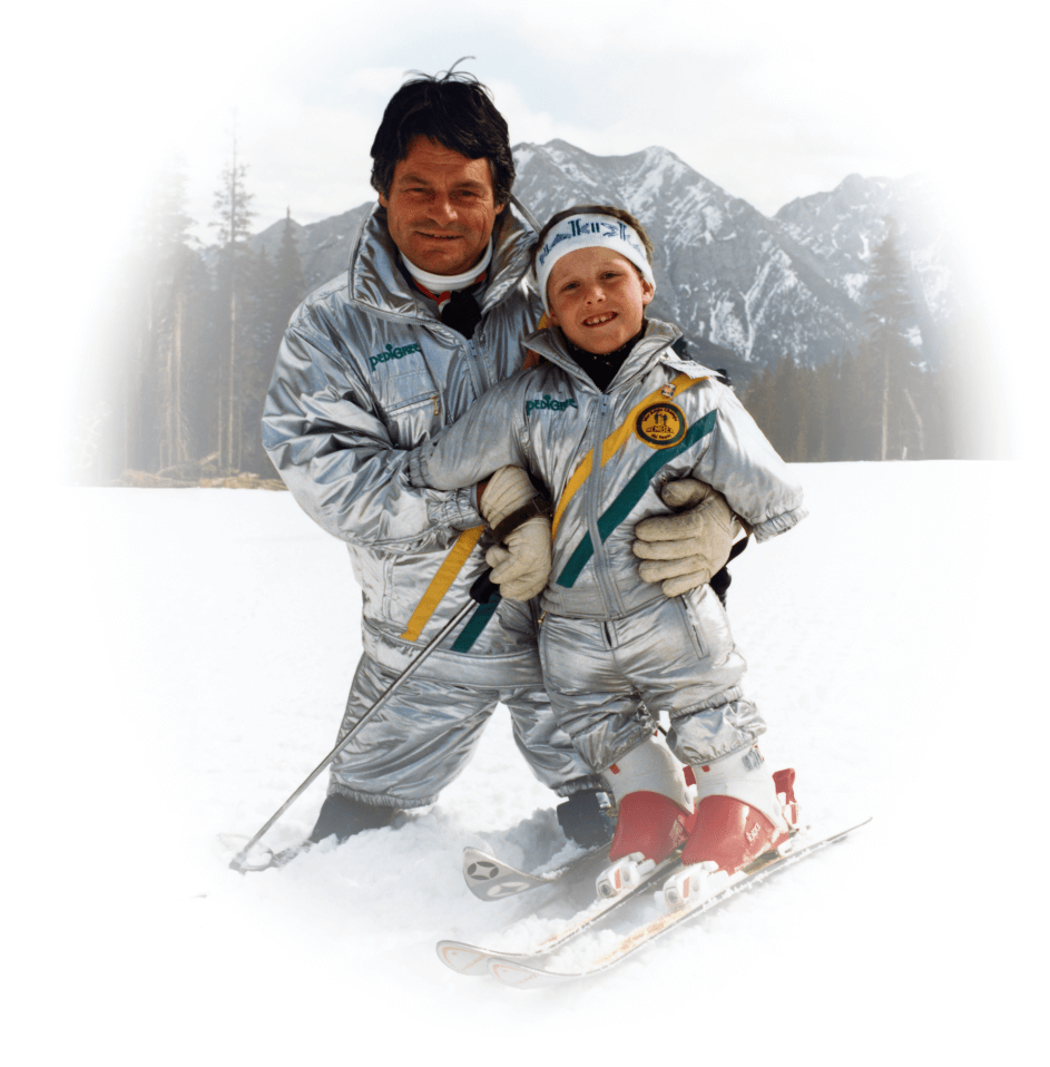 Karl Hilzinger et un enfant amputé sur une piste de ski avec des montagnes en arrière-plan.