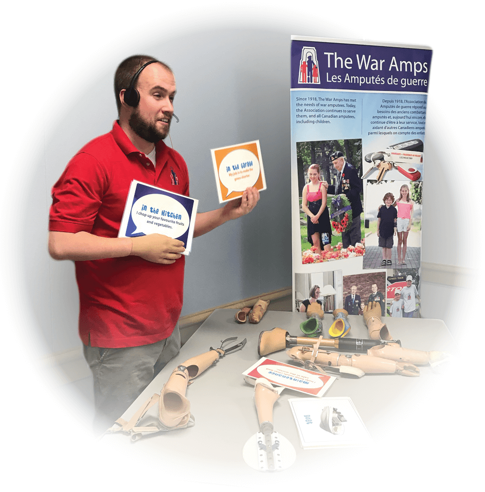 A male War Amps staff member, who is a partial hand amputee, holds props while giving a virtual presentation to students.