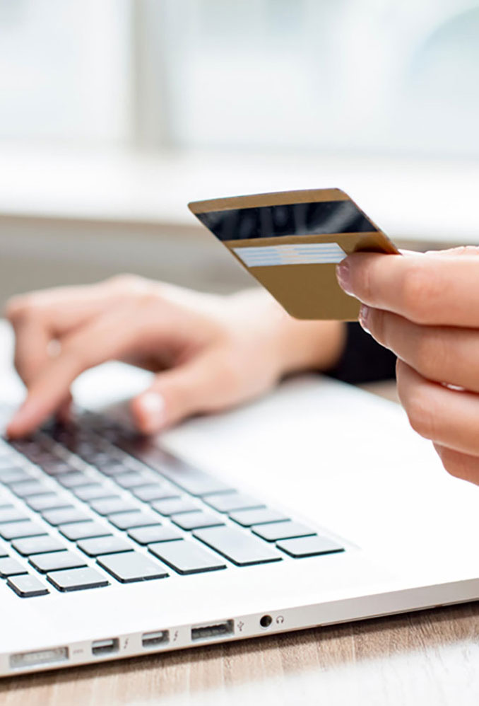 A person holding a credit card typing on a laptop.